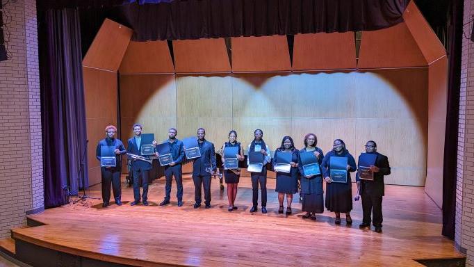 Image of young men and women dressed in concert attire displaying honors certificate.